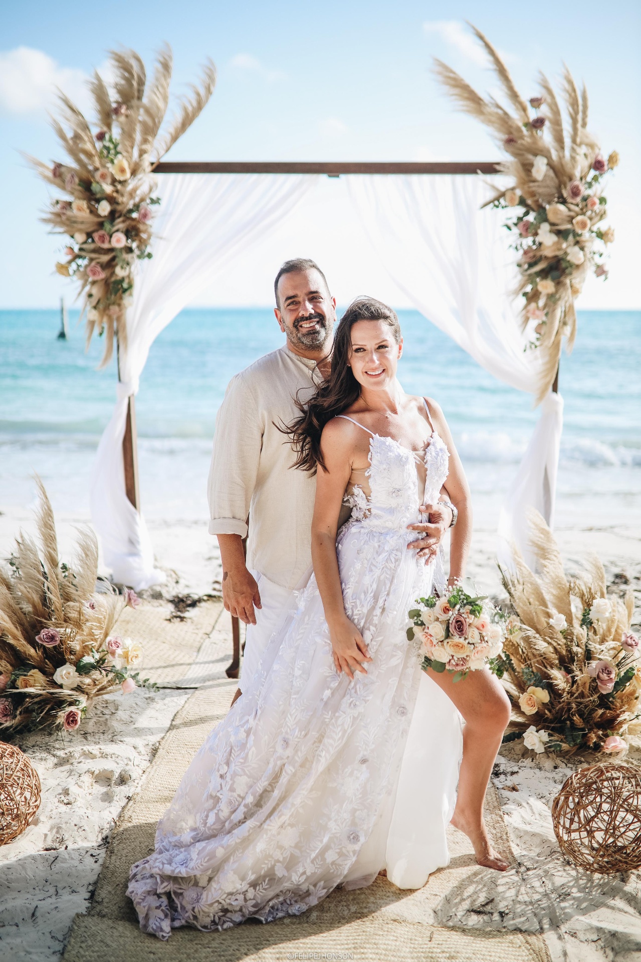 Noivos radiantes em altar elegante com vista para o mar azul turquesa